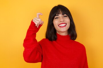 Caucasian brunette woman wearing red casual sweater isolated over yellow background pointing up with fingers number nine in Chinese sign language Jiu