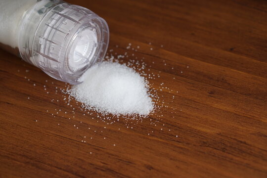 Close Up White Natural Organic Sea Salt Powder Flake Cook Ingredient In Grinder Bottle Glass On Vintage Rustic Black Kitchen Wooden Table