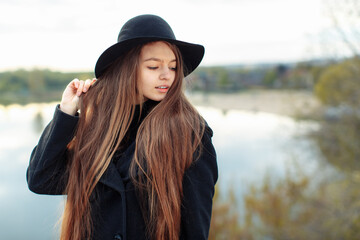 Close-up portrait of young beautiful fashionable woman in black hat on blurry background, long hair