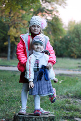 two sisters stand on a tree stump, hug and smile