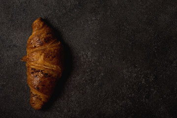 Classic French croissant with chocolate on a dark concrete background, copy space