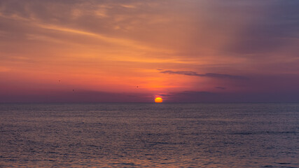 Beautiful orange sunset over the sea. The sun sets on the horizon. Relaxing sea landscape. Purple shades of sky and sea water. Sunset over the Black sea. The natural background.