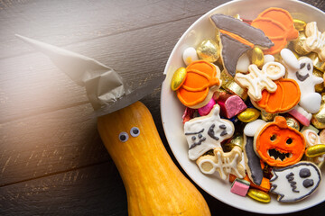 Halloween Jack o Lantern candy bowl with candy and halloween cookies Trick or Treat on black wooden background