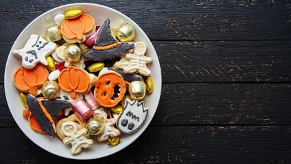 Halloween Jack o Lantern candy bowl with candy and halloween cookies Trick or Treat on black wooden background