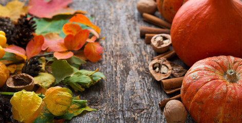 Autumn vegetables, fallen leaves, nuts and pumpkins on a wooden background, Thanksgiving concept, copy space