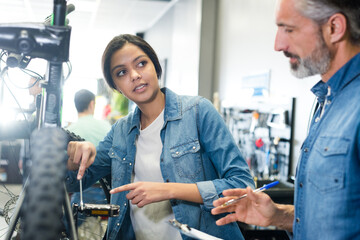 Obraz premium female bicycle mechanic and apprentice repairing a bike