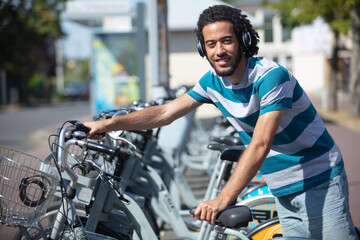 man wearing headphones parking rental bike