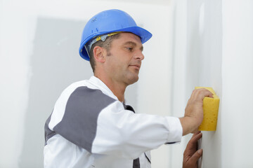 male builder using a sponge on a plastered wall