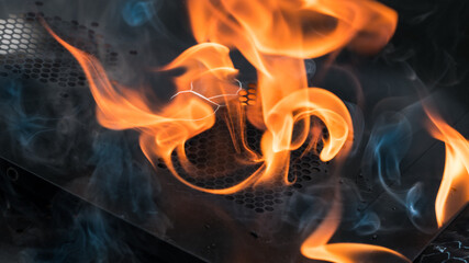 Blazing smoking fire in broken charred wreck part on black background. Artistic detail of orange...