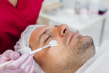 A young man is undergoing a cosmetic facial peeling procedure. Cosmetology and rejuvenation