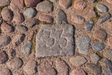 old stone figures on the pavement in the masonry on the square figure 33 middle ages market square, numbers on the pavement