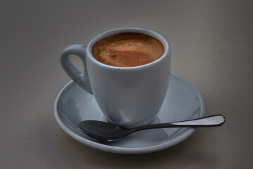 Fototapeta premium Delicious coffee in a white porcelain cup, with saucer and teaspoon
