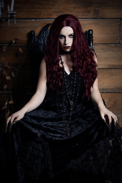 A young woman sits on a black gothic throne in a Halloween themed image