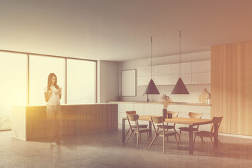 Young woman standing in white and wooden kitchen