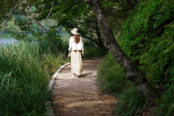 Fototapeta premium Young woman traveler walking on wooden path trail in Plitvice Lakes National Park, UNESCO natural world heritage and famous travel destination of Croatia