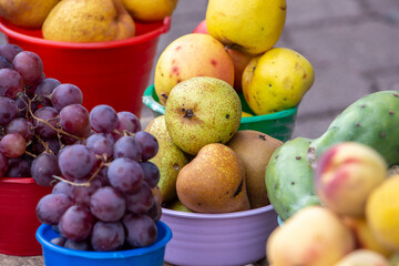 Fruta orgánica en baldes de colores, peras, uvas, duraznos, tunas, rambután.