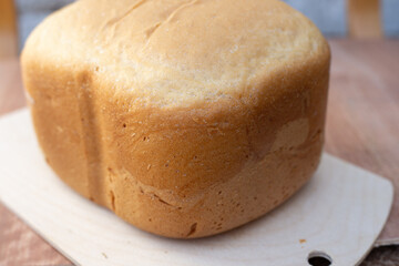 close-up of white bread on a wooden board freshly baked in an electric bread maker. Homemade baking