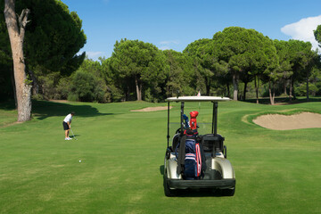 Golf cart with golf clubs on a green  professional golf field