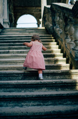 little girl in pink dress goes up stairs