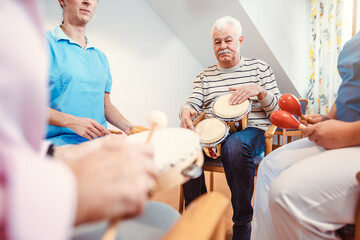 Seniors in nursing home making music with rhythm instruments