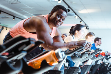 Fototapeta na wymiar African man and friends on fitness bike in gym