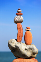 Two Rock zen pyramids of colorful pebbles on a beach on the background of the sea.