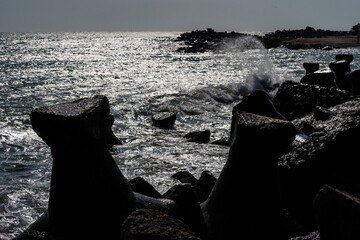 Agitated sea waves splashing into the coastline rocks on an autumn offseason morning. - 381210320