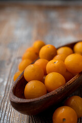 Heap of small yellow cherry tomatoes in a wooden bowl, close up, macro