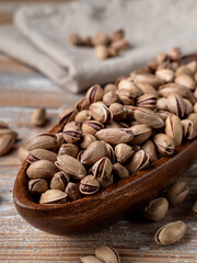 Pile of unpeeled salted pistachios in a wooden bowl, pistachios platter for a party