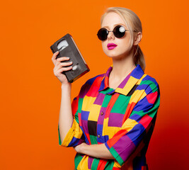Style blonde in 90s clothes with VHS cassette