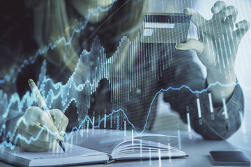 Double exposure of woman on-line shopping holding a credit card and financial graph drawing. Stock market E-commerce concept.