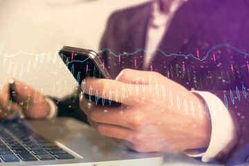 Multi exposure of man's hands holding and using a digital phone and forex graph drawing. Financial market concept.