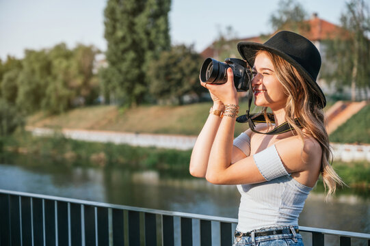 Young tourist woman using her professional camera and taking photos outdoors