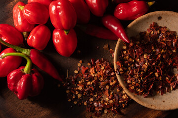 Assorted hot chilli pepper and crushed peppers on wooden surface. Ideal for food recipe or...