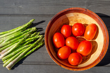 asparagus and tomatoes, natural farm food, wooden bowl and wooden background