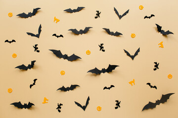Halloween decorations with pumpkin and bats on pastel beige background. Halloween concept. Flat lay, top view, copy space