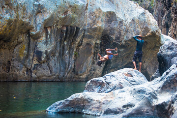 Somoto Canyon, Nicaragua. Two young man enjoying the natural scenery, jumping into the calm waters. Rocky mountains surroundings. Beautiful dry summer landscape, Central America.