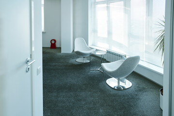 Two soft comfortable armchairs surrounding small round table by large window