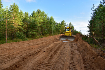 Dozer during clearing forest for construction new road . Yellow Bulldozer at forestry work Earth-moving equipment at road work, land clearing, grading, pool excavation, utility trenching © MaxSafaniuk