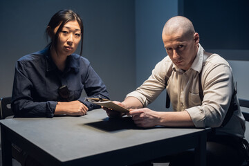 An experienced police officer and his young assistant sit at the table and sort out the case.