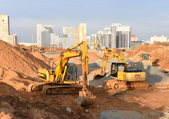 Group of the excavators working on dig ground trenching at construction site. Backhoe on groundwork...
