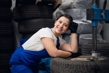 Car service worker posing next to wheels and a machine tool