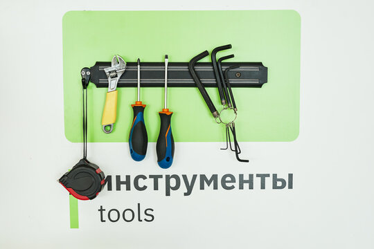 Background image of magnetic tool rack with wrenches and screwdrivers over word TOOLS written in English and Russian - Powered by Adobe