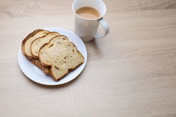 Slices of bread in a plate and a cup of coffee on a wooden table 