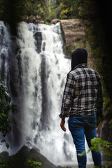 Fototapeta na wymiar Solo man discovering waterfall in middle of forest. Inspirational and travel concept