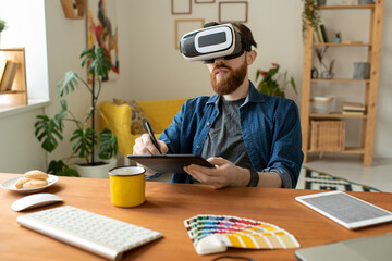 Young contemporary creative designer in vr headset drawing on tablet with stylus