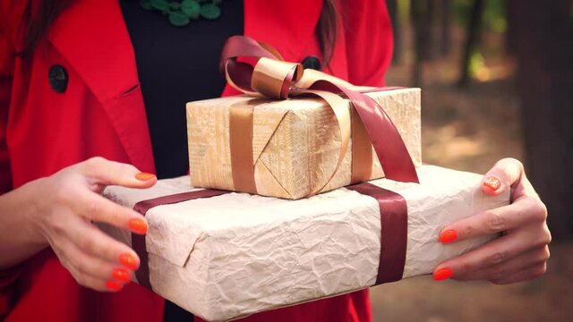 wrapped gifts. close up. woman holding several beautifully packed boxes in her hands. outdoors. delivery or donation, charity concept. gifts for the holiday