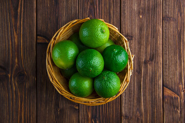 Limes in a wicker basket on a wooden background. flat lay.