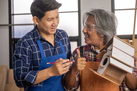 Two carpenters working on handmade wooden product using professional tools at workshop to produce construction material or wooden furniture . DIY maker and carpentry work concept.