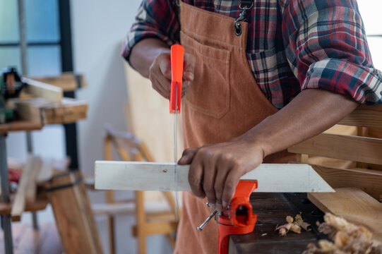 Carpenter working on wood craft using saw and ruler tools for hand crafting at workshop to produce construction material or wooden furniture . DIY maker and carpentry work concept.